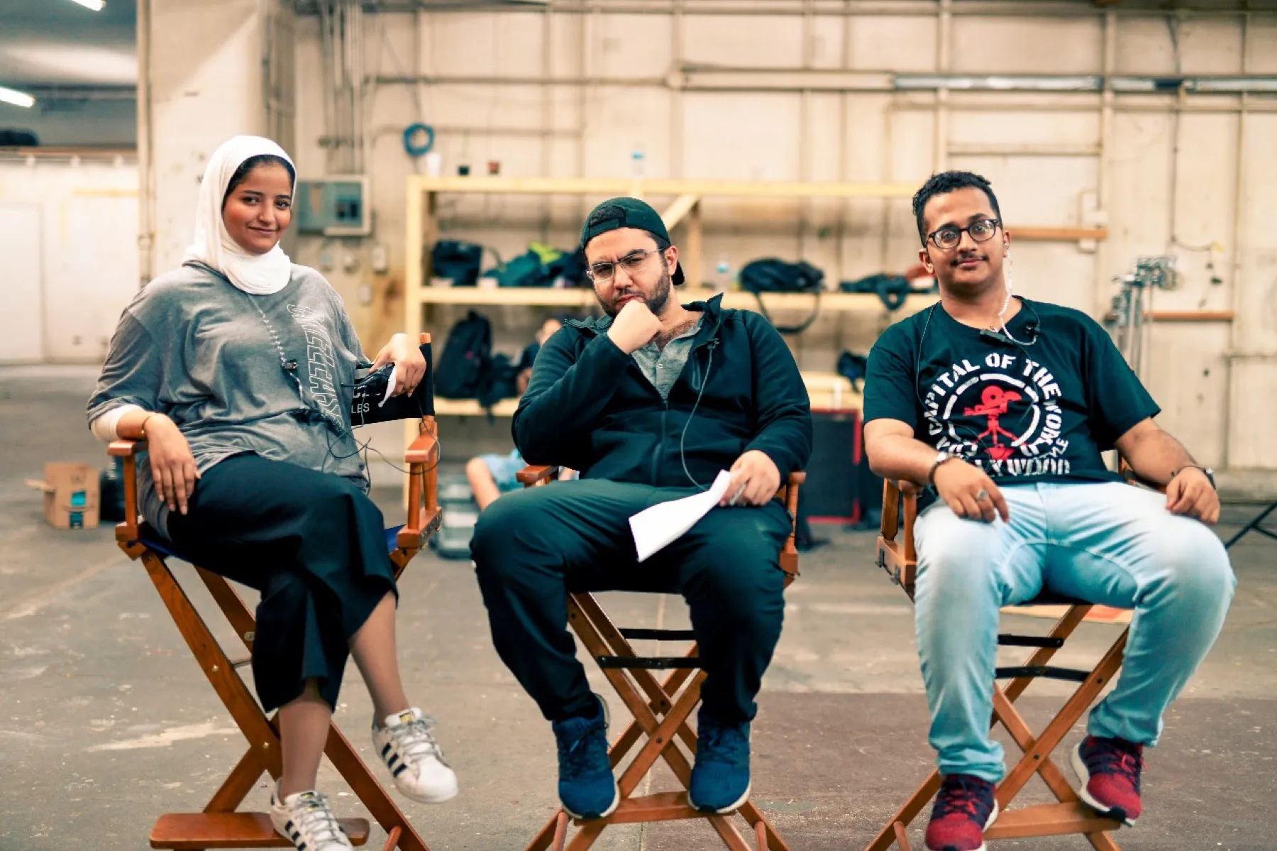 Three crew trainees seated in director&rsquo;s chairs on a training stage.