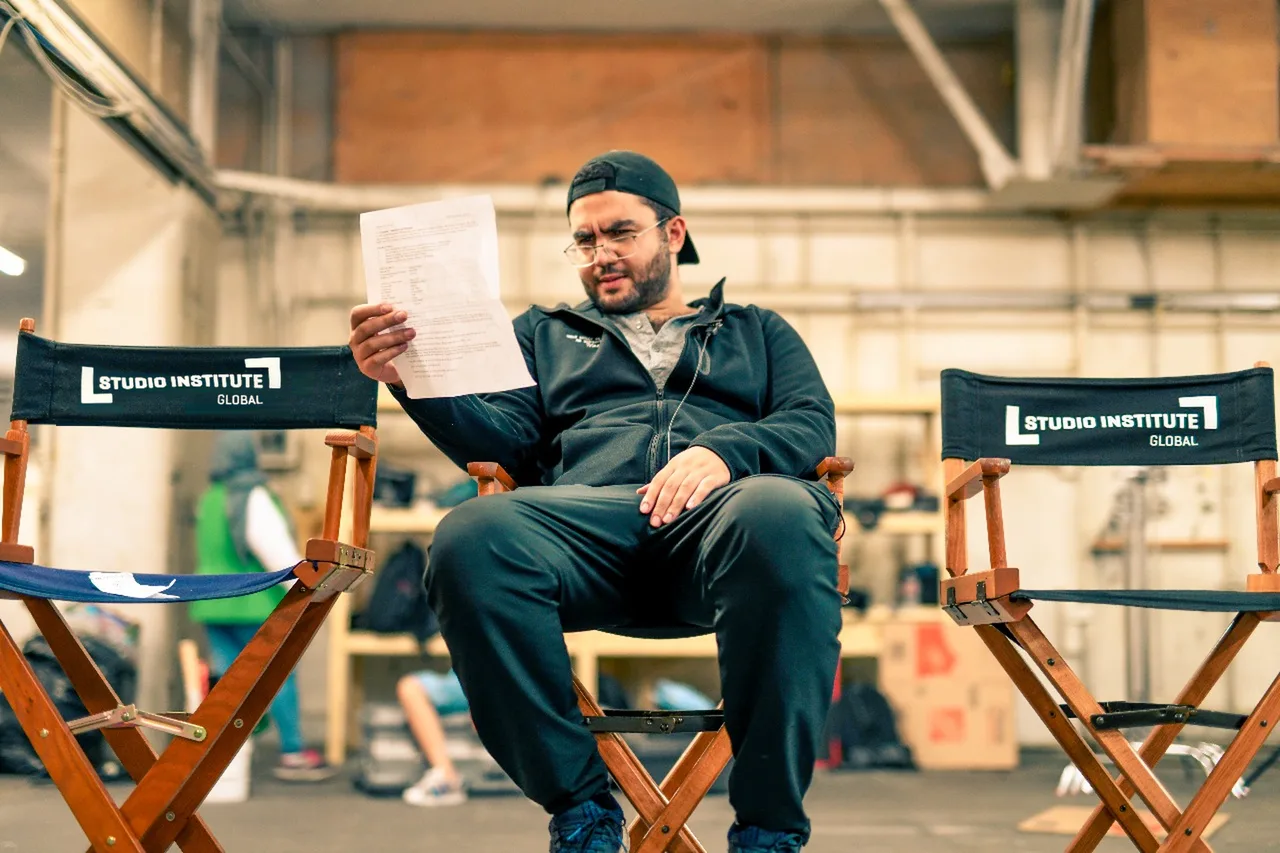 A crew member reading a script in a Studio Institute Global director&rsquo;s chair on a working stage.