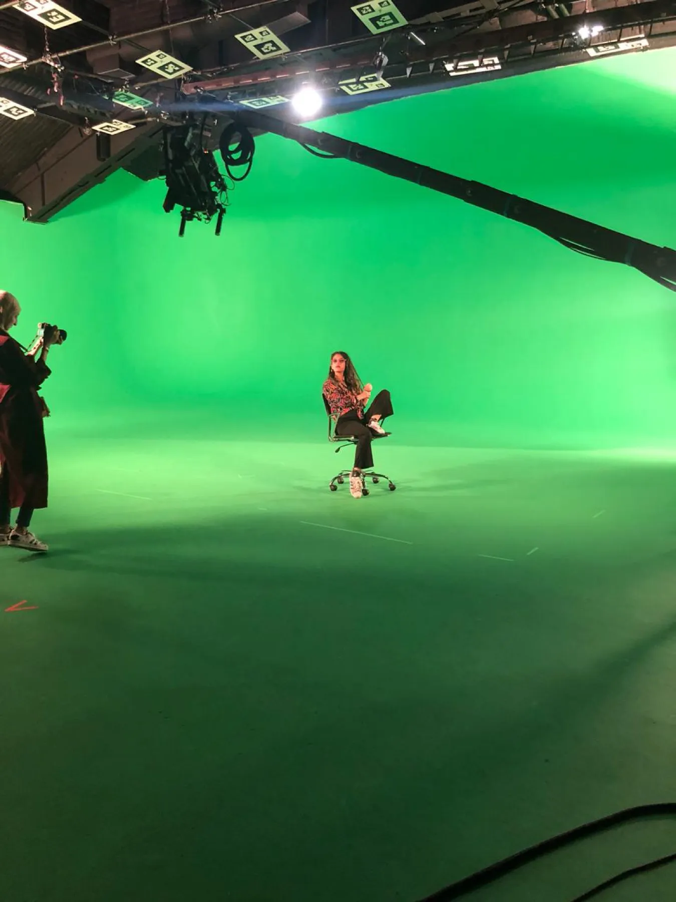 A trainee seated on a green-screen stage under a camera crane during a Studio Institute Global crew-training production.