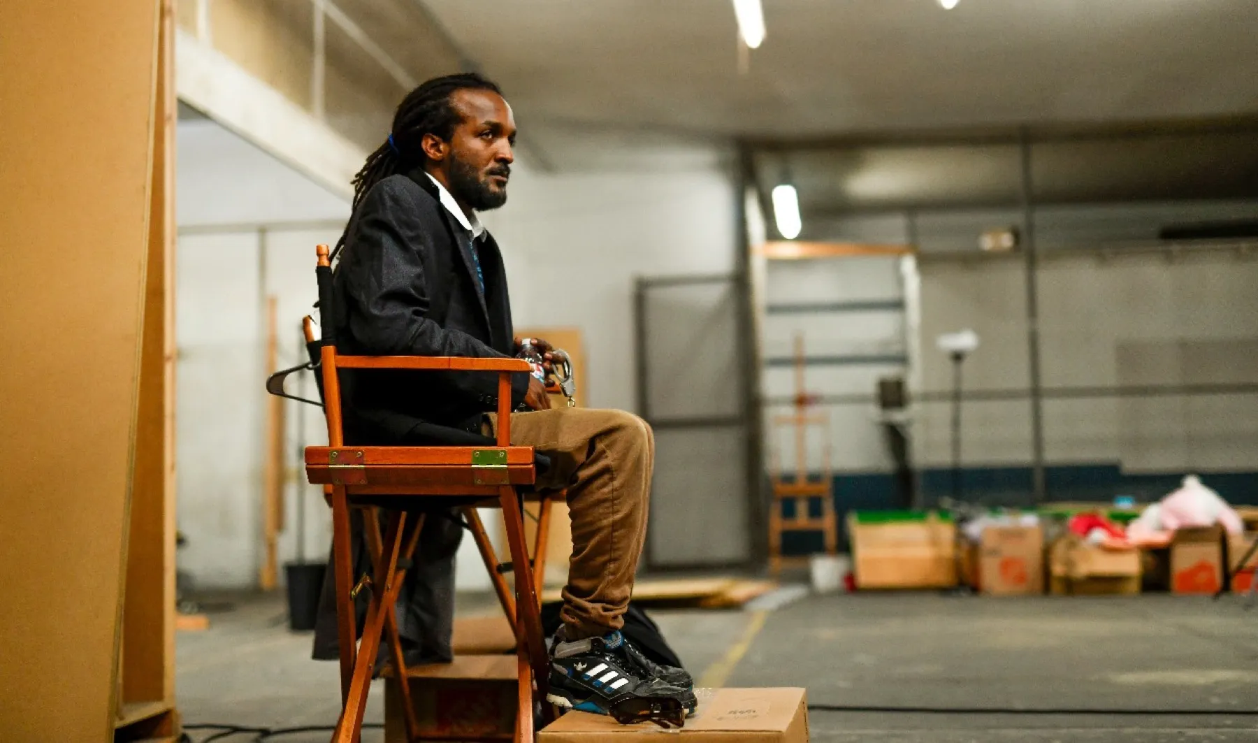 A crew member seated in a director&rsquo;s chair on a quiet stage at the end of a training day.